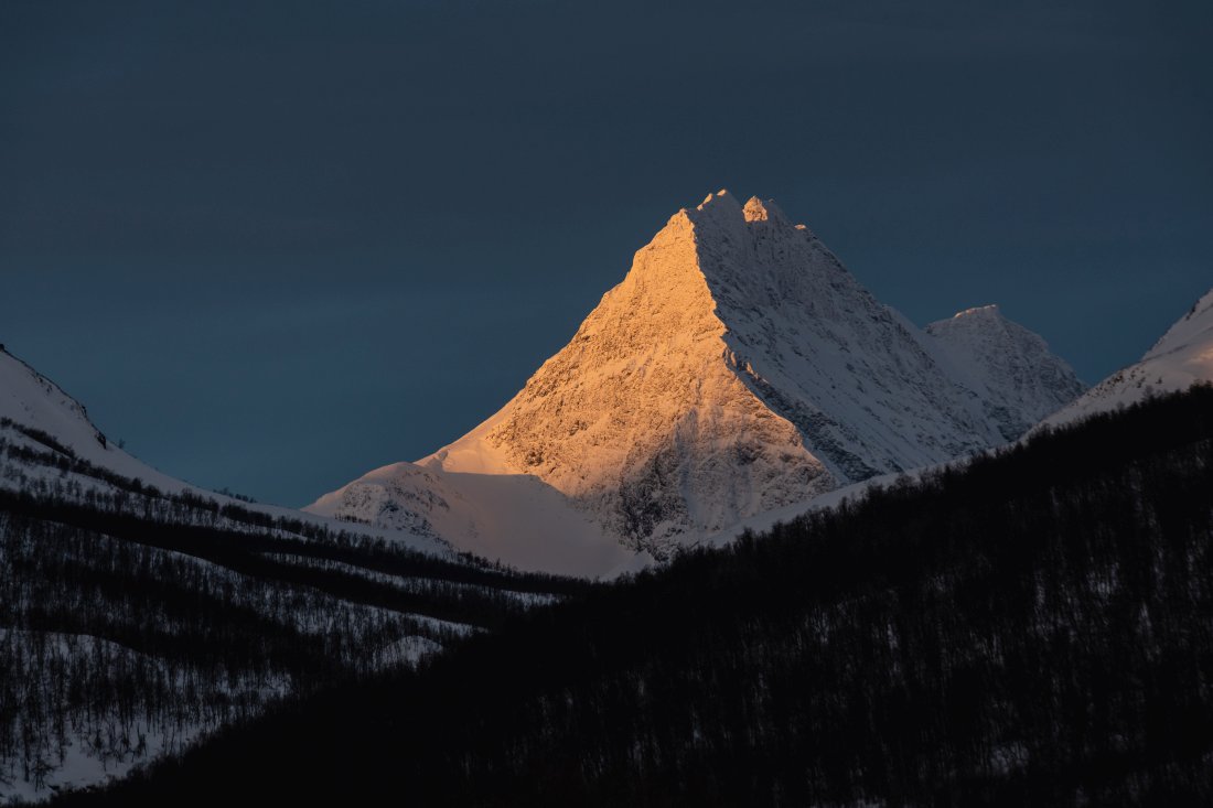 Face enneigée d'une montagne au lever de soleil en Norvège